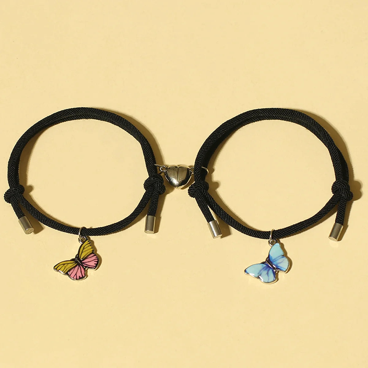 Two black hair ties with butterfly charms on a beige background