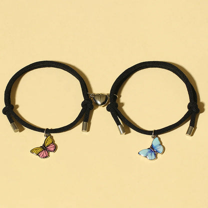 Two black hair ties with butterfly charms on a beige background